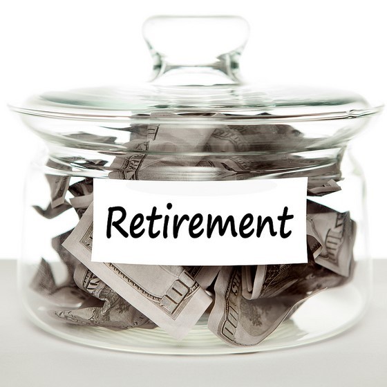 A glass jar labeled retirement is filled with cash.